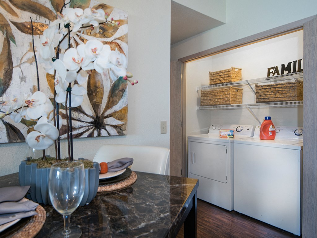 a kitchen with a washer and dryer and a table with a vase