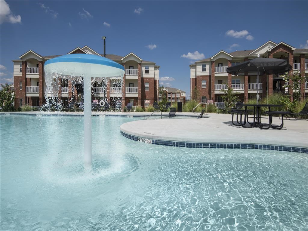 a large pool with a fountain in front of an apartment building