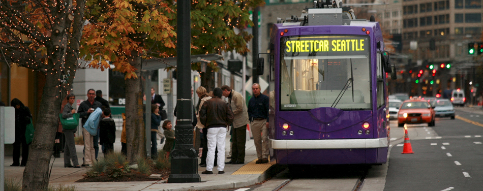 a purple streetcar stopped at a bus stop on a city street