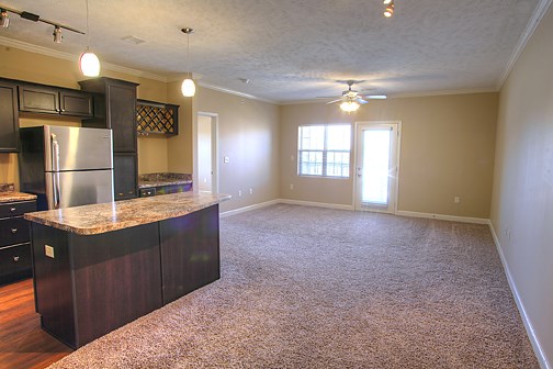 an empty kitchen and living room with a granite counter top
