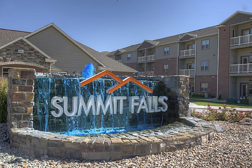 a sign for summit falls in front of an apartment building