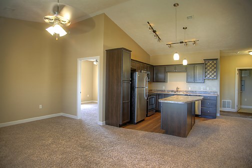 an empty kitchen with a stainless steel refrigerator and an island