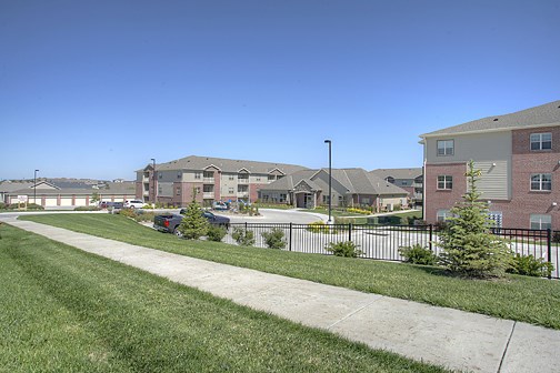 an apartment complex with a sidewalk and green grass