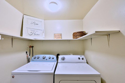 two washers and a dryer in a laundry room with a shelf above them