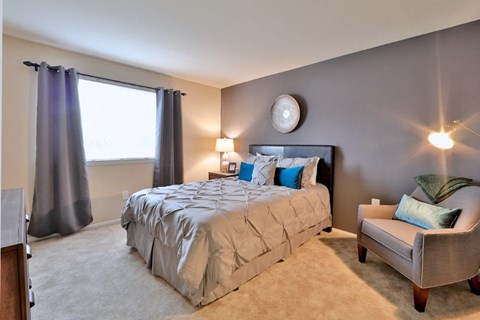 a bedroom with a bed and a chair and a window