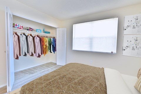 a bedroom with a bed and a closet with clothes on a rack