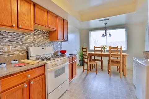 a kitchen with a stove and a table with wooden chairs