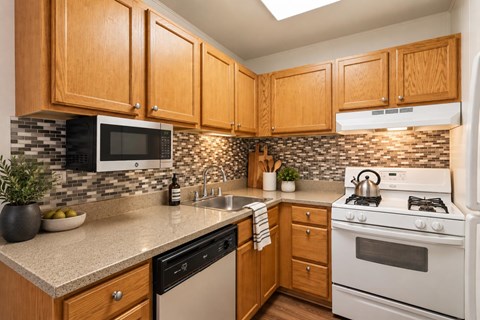A kitchen with wooden cabinets and a white stove top oven.