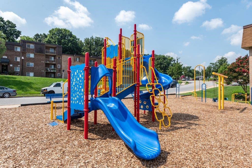 a playground with a blue slide and red and yellow equipment