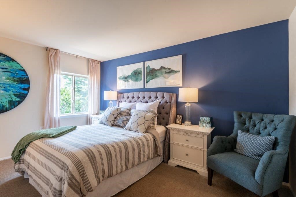 a bedroom with a bed and a chair and a window