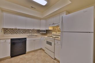 a kitchen with white cabinets and a refrigerator
