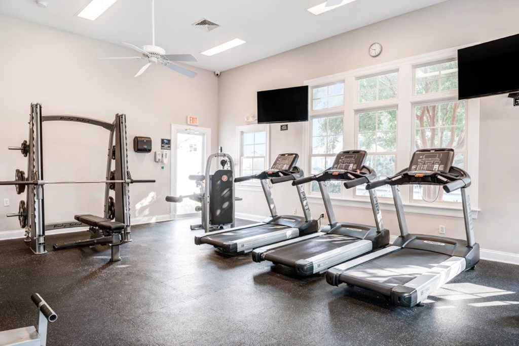A gym with treadmills, weights, and a television.