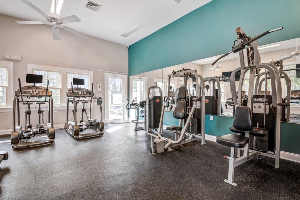 A gym with a variety of equipment including a rowing machine, a leg press machine, and a chest press machine.