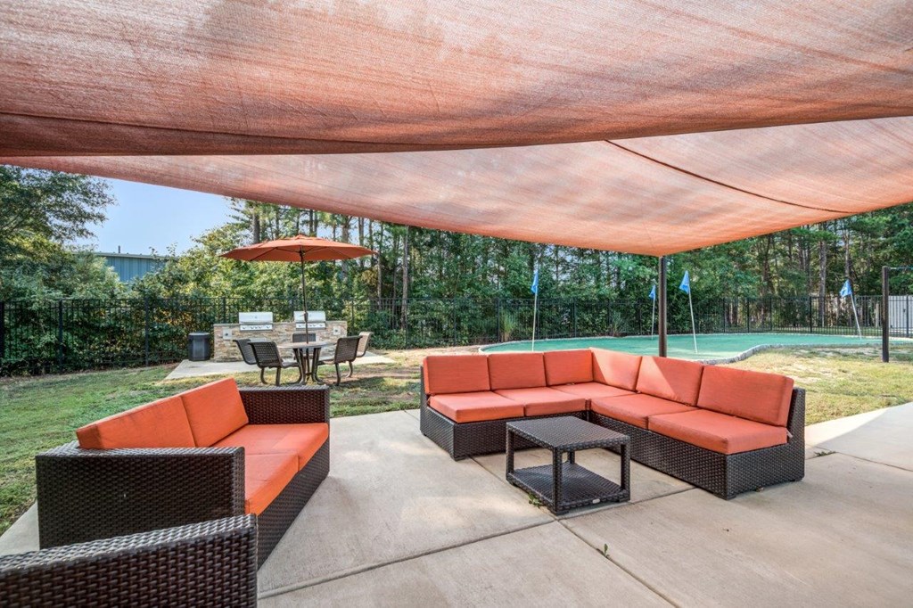 A patio with a red canopy and black wicker furniture.