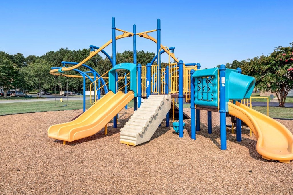 A playground with a yellow slide and blue and yellow play structure.