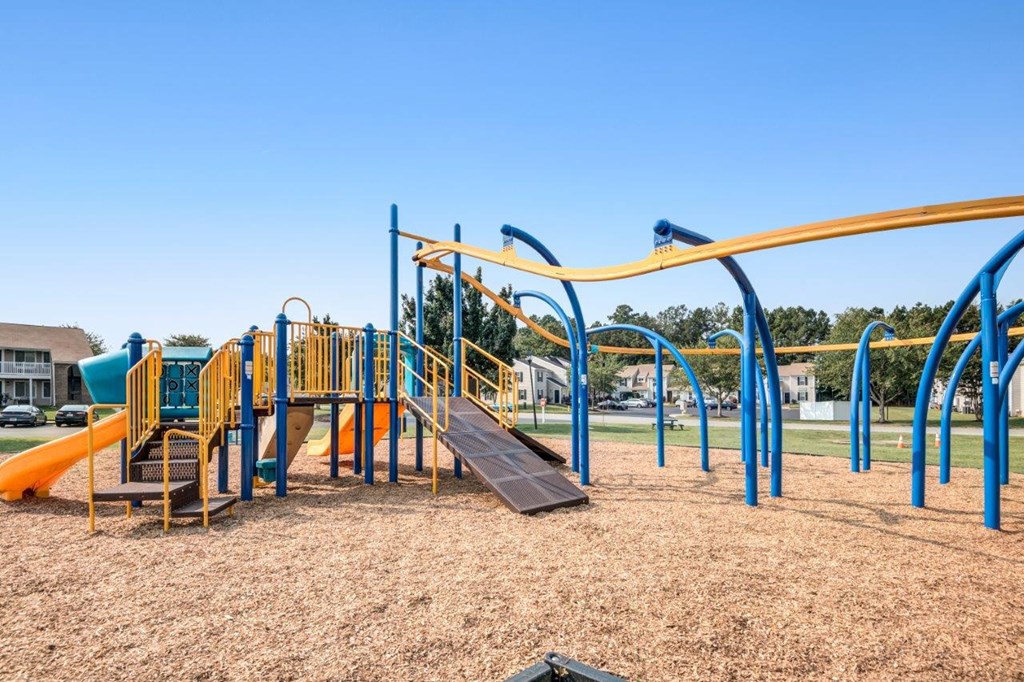 A playground with a blue and yellow structure and a slide.