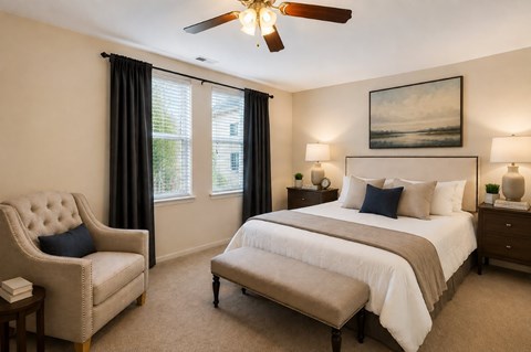 A bedroom with a large bed, a chair, and a ceiling fan.