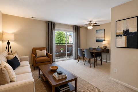 A living room with a white couch, a brown armchair, a wooden coffee table, and a dining table with chairs.
