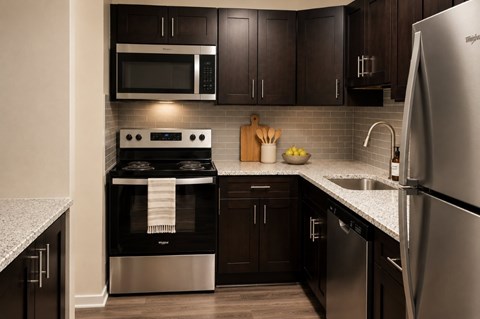 A modern kitchen with dark wood cabinets and stainless steel appliances.