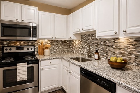 A kitchen with white cabinets and a black stove top oven.