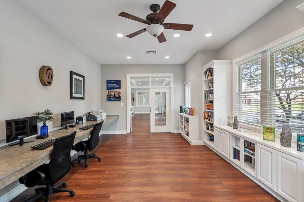 A home office with a desk, chairs, and a ceiling fan.