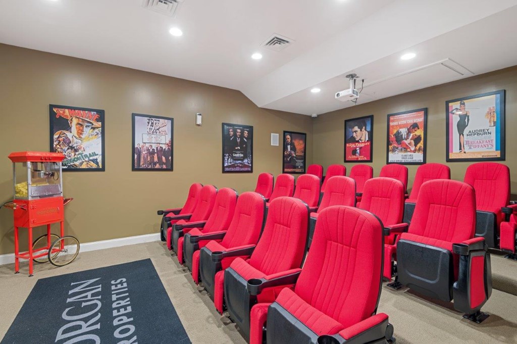 A row of red seats in a room with posters on the wall.