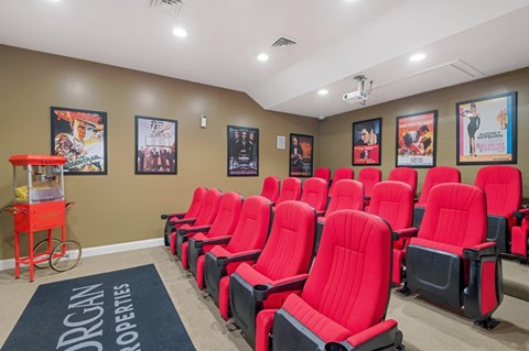 A row of red seats in a room with posters on the wall.