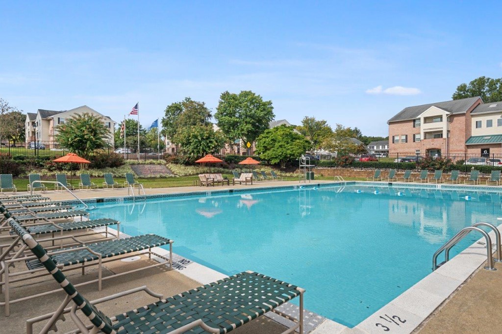 A large swimming pool with lounge chairs and umbrellas.