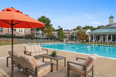 A poolside area with striped chairs and an orange umbrella.