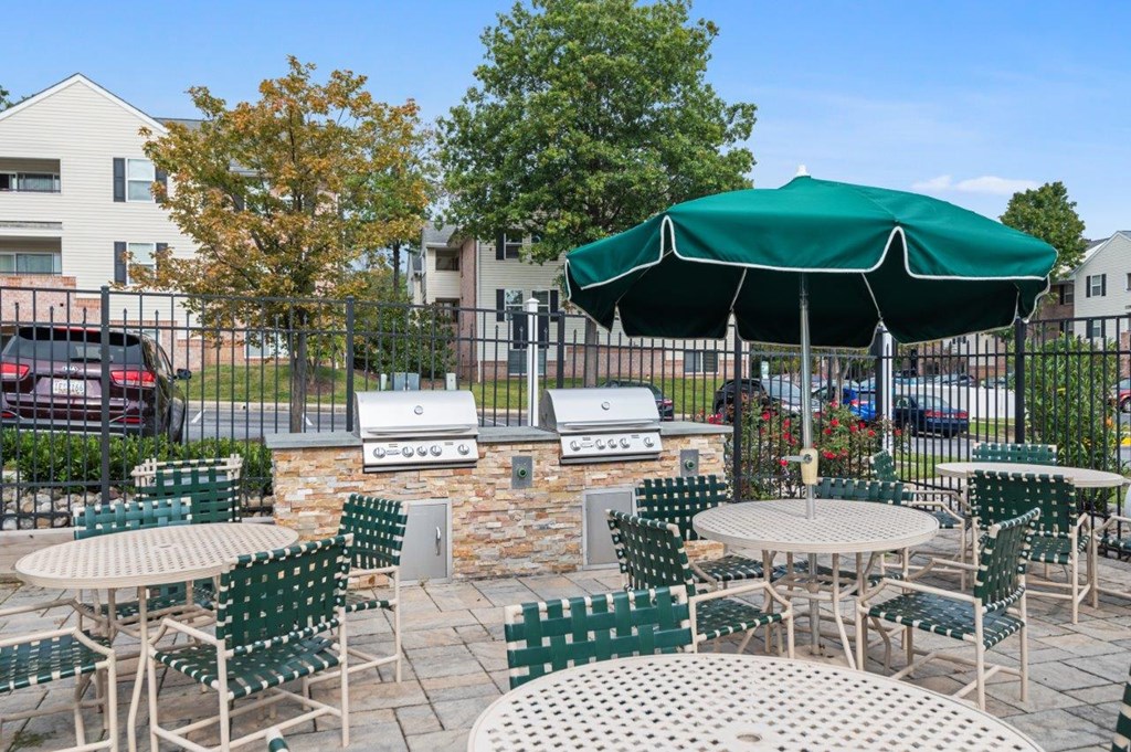A patio with tables and chairs and a green umbrella.