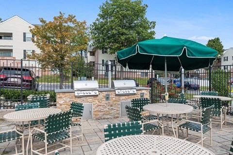 A patio with tables and chairs and a green umbrella.