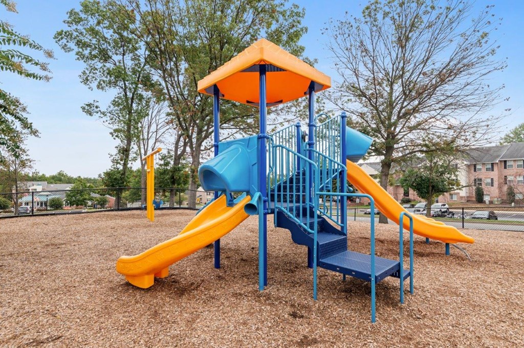 A playground with a blue and yellow slide and a yellow and blue tower.