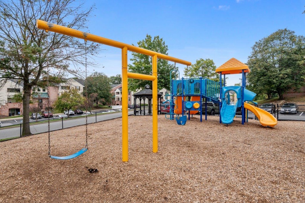 A playground with a yellow swing set and a blue slide.