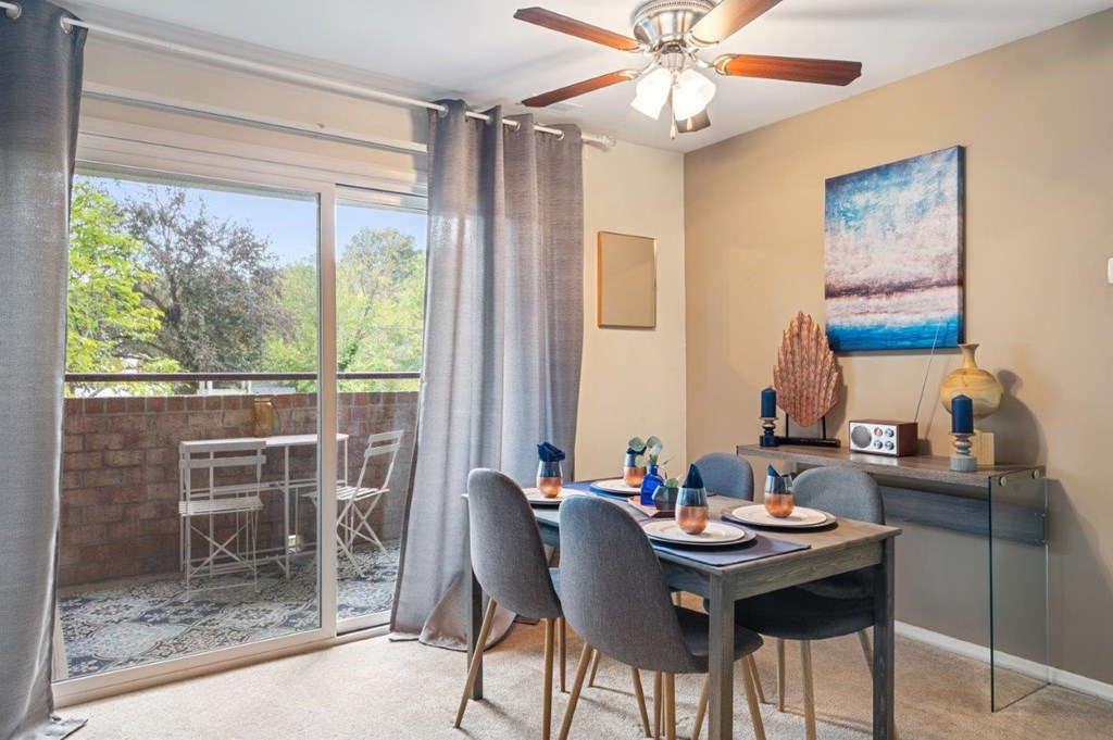 A dining room with a table set for two and a view of the backyard.