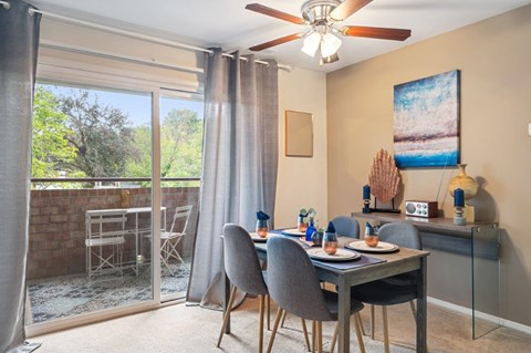 A dining room with a table set for two and a view of the backyard.