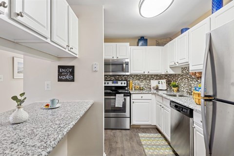 A kitchen with a granite countertop and stainless steel appliances.