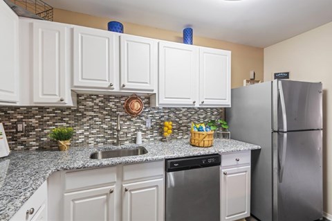 A kitchen with a refrigerator, dishwasher, and sink.