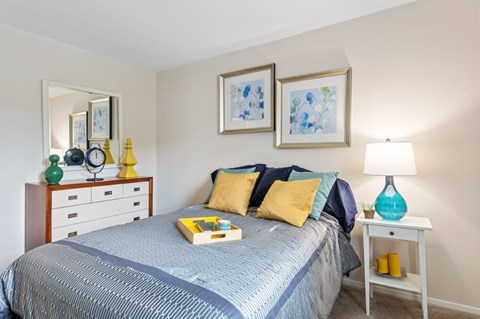 A bedroom with a bed, nightstand, and lamp.