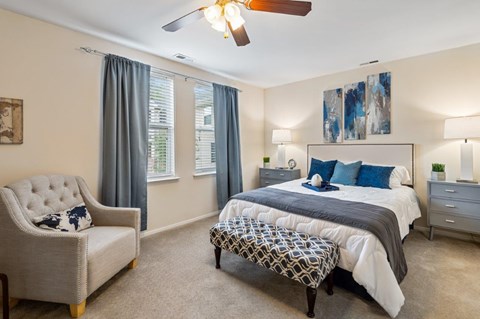 A bedroom with a large bed, a chair, and a ceiling fan.