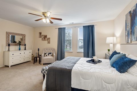 A bedroom with a large bed, a dresser, a mirror, and a ceiling fan.