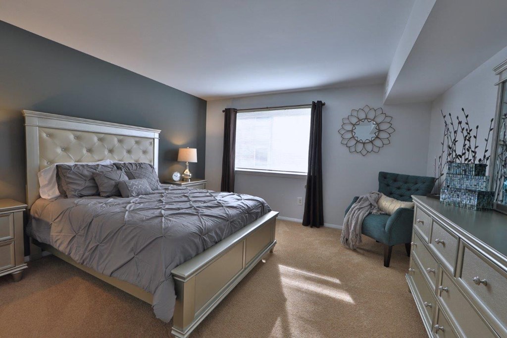 a bedroom with a bed and a chair and a window