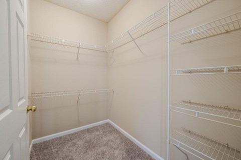 a spacious closet with white shelves and a door
