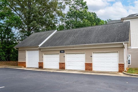 a garage with three white garage doors on the side of a house