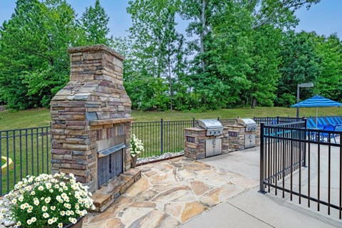 a backyard with a stone fireplace and a grill