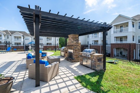 A patio with a fireplace and seating area under a pergola.