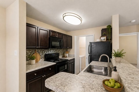 A kitchen with a granite countertop and a black stove top oven.