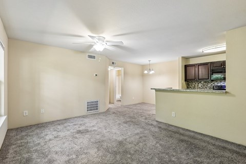 A spacious room with a ceiling fan and a counter with a microwave.