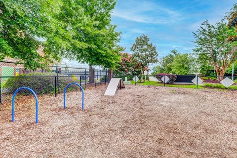 a playground in a park with trees and a chain link fence
