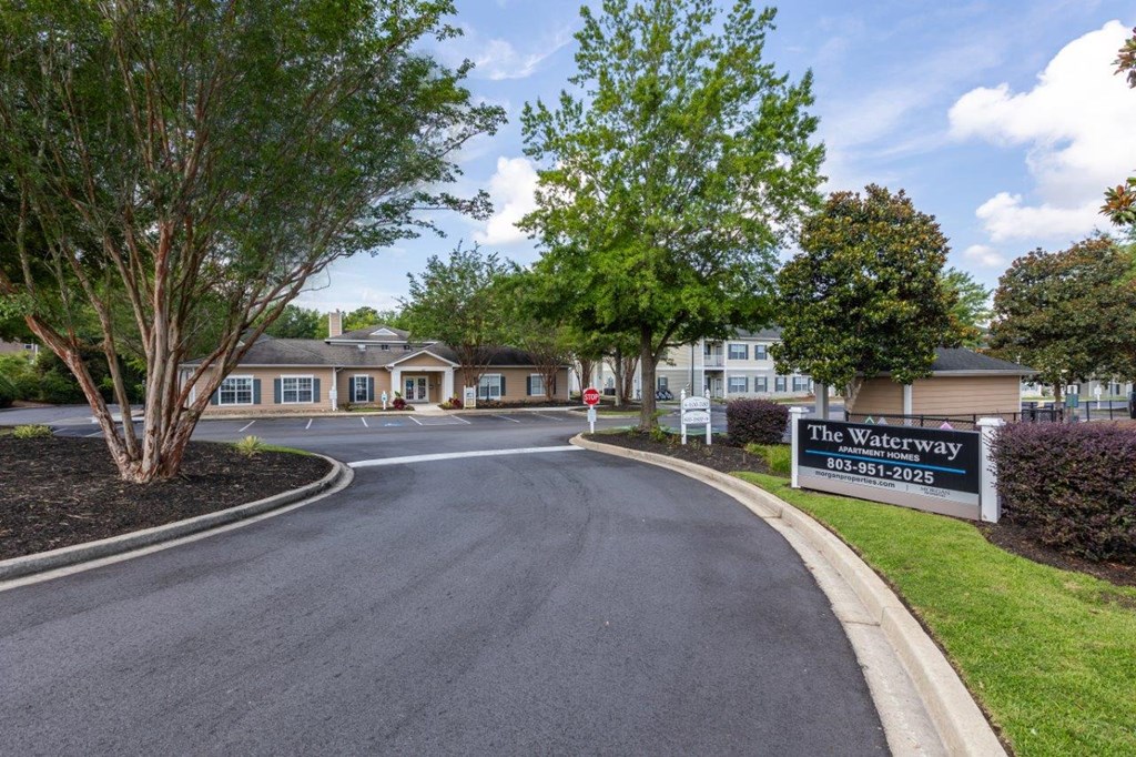a street with a sign for the waterway at the entrance to an apartment building