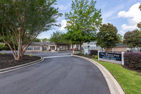 a street with a sign for the waterway at the entrance to an apartment building